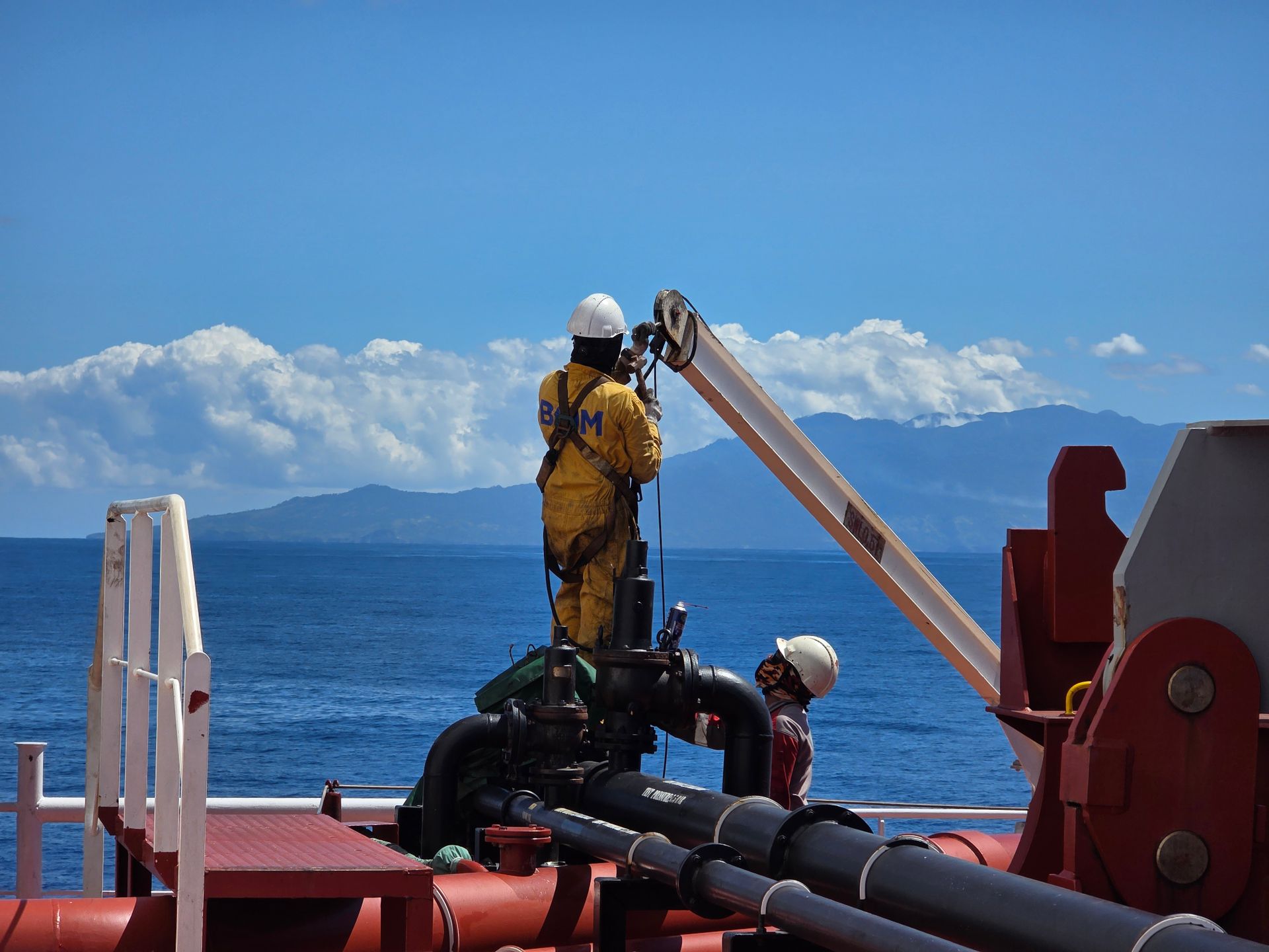Técnico com capacete e EPI trabalhando em embarcação offshore